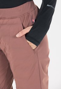 Bruine gewatteerde broek met een ritszak, met een zachte textuur en een getailleerd ontwerp. De tailleband is iets hoger voor een veilige pasvorm.