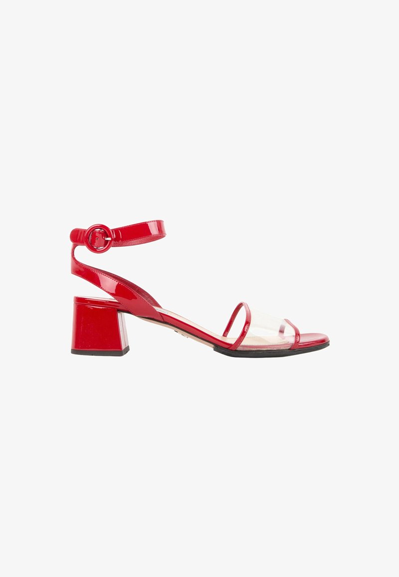 Sandale en cuir verni rouge avec talon bloc, bride avant transparente et bride de cheville avec boucle ronde sur fond blanc.