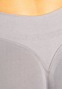 Top atletico grigio con una texture a costine, caratterizzato da un design aderente e da un logo stampato sopra la cucitura, che enfatizza una silhouette elegante.