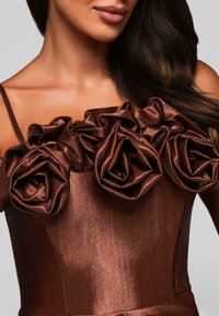 Hnědress s dobře padnoucí korzetovou částí, která má velké, texturované aplikace ve tvaru růží podél výstřihu. Materiál má jemný lesk.