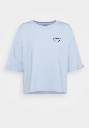 Hellblaues oversized T-Shirt mit kurzen Ärmeln, aufgerollten Ärmelbündchen und kleinem schwarzen "happy"-Schriftzug sowie Smileygrafik auf der oberen linken Brust.