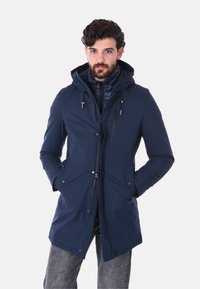 Parka di colore blu navy con zip anteriore, cappuccio regolabile e tasche laterali. Presenta una superficie esterna liscia e un rivestimento interno trapuntato.