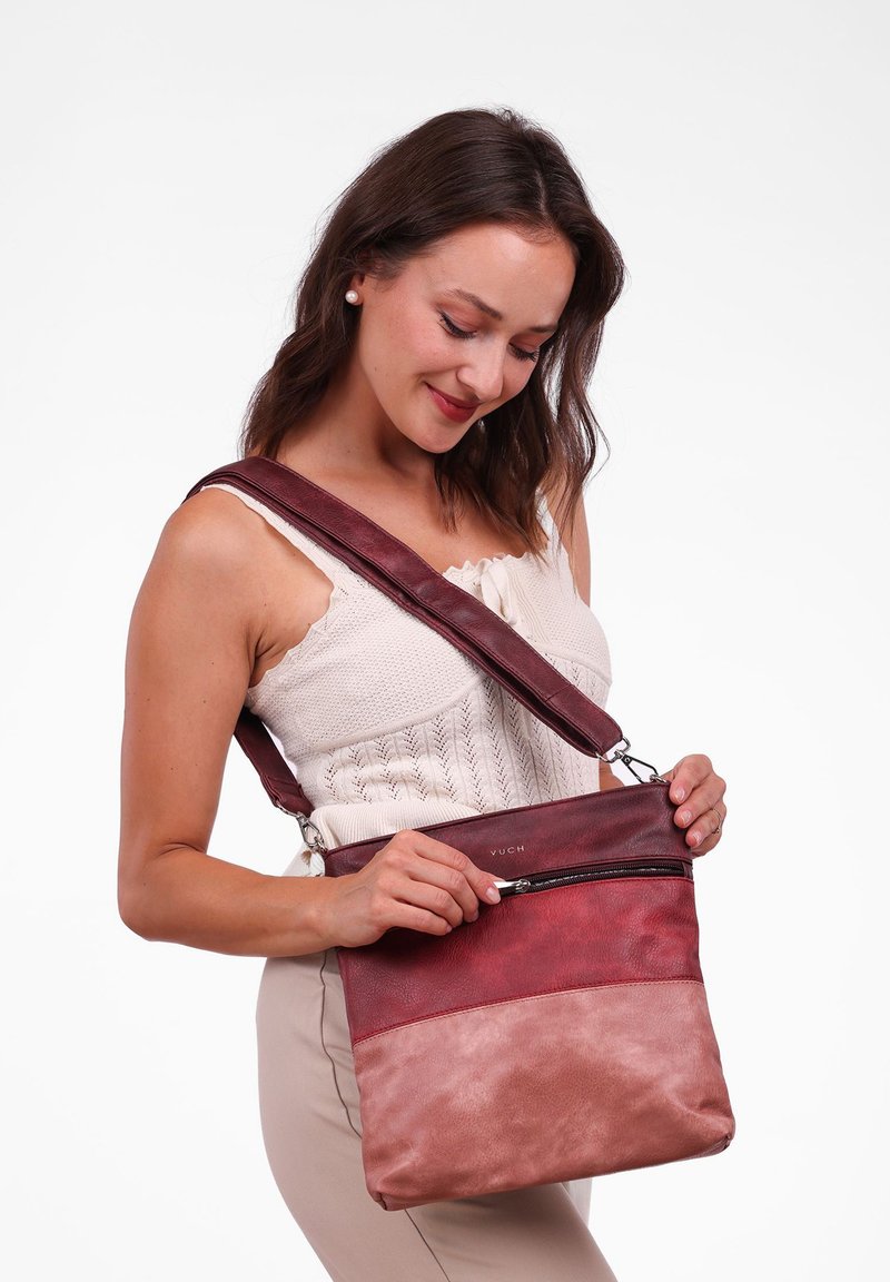 Červená a růžová kožená crossbody taška s nastavitelným popruhem, která má zipovou přední kapsu a texturovaný barevný blokový design.