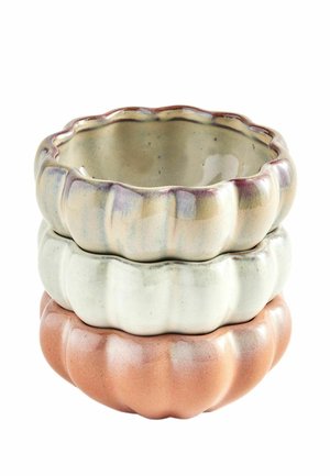 Tre keramiske skåle stablet, hver med en bølget kant og græskar-lignende riller, farvet beige, hvid og terracotta.