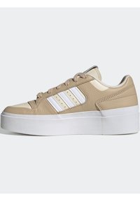 Beige ja valge madalate sneakerite jalats paksu valge platvormi tallaga, beige paelad ja valged triibud küljel, nähtud külgprofiilis.