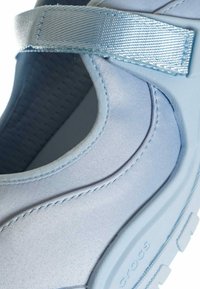 Scarpa slip-on azzurro chiaro in materiale liscio, con suola texturizzata e cinturino blu lucido sulla parte superiore per una calzata sicura.
