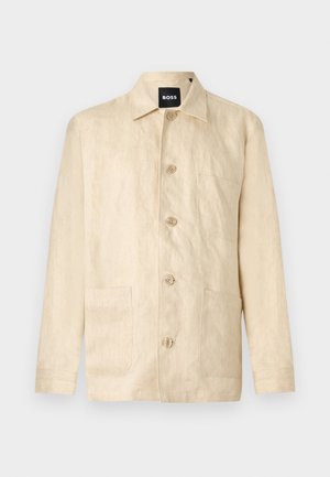 Veste beige à manches longues avec col, trois poches avant et une étiquette "BOSS" visible au niveau du col.