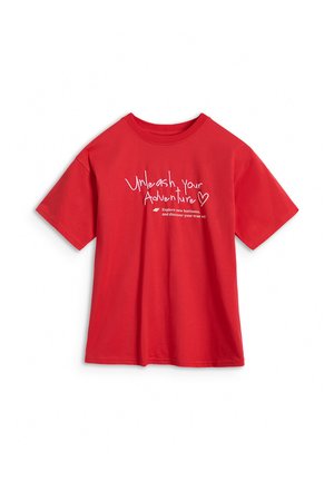 Czerwony t-shirt z krótkim rękawem z białym napisem "Uwolnij swoją przygodę" oraz mniejszym tekstem poniżej na jednolitym białym tle.