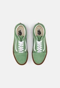 Green suede sneakers with white accents, featuring a lace closure, round toe, and gum rubber outsole. Vans logo visible on the tongue.