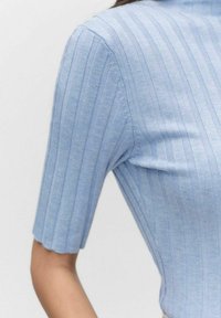 Jasnoniebieski top dzianinowy z krótkimi rękawami i dopasowanym krojem. Materiał ma subtelną teksturę z pionowymi paskami.