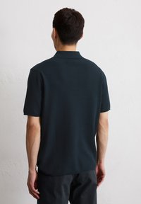Granatowa koszulka polo z krótkim rękawem, wykonana z teksturowanej tkaniny i z klasycznym kołnierzykiem, z bocznymi wentylami i luźnym krojem.
