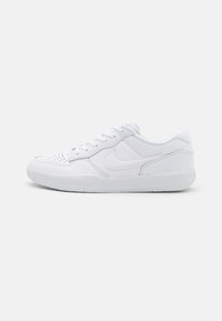 Sneaker Nike blanc bas avec embout perforé, fermeture à lacets et logo swoosh sur le côté, présenté sur un fond blanc uni.