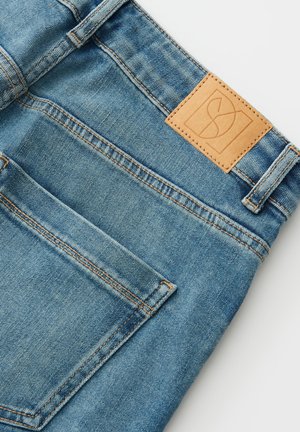Hellblaue Jeans aus Denim mit einem braunen Lederpatch mit Logo, kontrastierenden Nähten und einer Gesäßtasche. Sauberes, strukturiertes Gewebe.