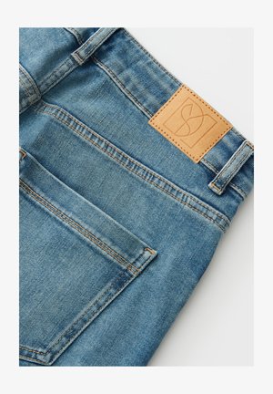 Hellblaue Jeans aus Denim mit einem braunen Lederpatch mit Logo, kontrastierenden Nähten und einer Gesäßtasche. Sauberes, strukturiertes Gewebe.