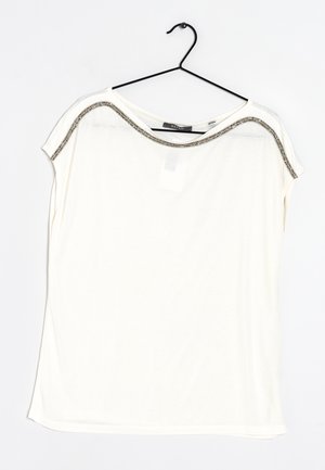 T-shirt bianco a maniche corte con vestibilità rilassata, caratterizzato da un colletto con accenti metallici e un tessuto morbido e leggero. Appeso a un gancio nero.