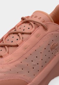 Ροζ αθλητικό παπούτσι με υφασμάτινο επάνω μέρος, τρύπες για αναπνοή και χαρακτηριστικό σχέδιο κορδονιών. Διαθέτει ανάγλυφο λογότυπο στη γλώσσα.