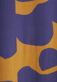 Textiel met abstracte vormen in diep paars en fel oranje. Het oppervlak heeft een gestructureerde weving, met vloeiende, soepele lijnen.