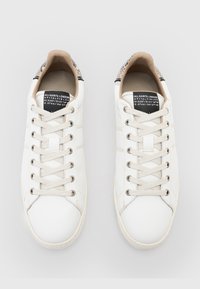 Weiße Ledersneaker mit runder Spitze, textile Akzente an der Ferse und flachen Schnürsenkeln. Die Zunge zeigt ein Markenlabel und Modellinformationen.