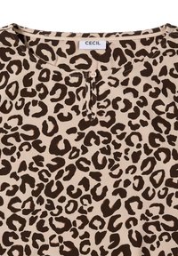 Blusa de estampado de leopardo con fondo beige, que presenta manchas marrón oscuro, un escote redondeado y un detalle de botón en el frente. Etiqueta: CECIL.