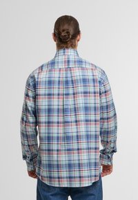 Koszula w kratę z długim rękawem w odcieniach niebieskiego, zielonego i czerwonego. Luźny fason z kołnierzykiem zapinanym na guziki i regulowanymi mankietami. Materiał z mieszanki bawełny.