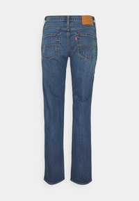 Jean bleu droit en denim vu de dos avec deux poches arrière, détails de couture et un patch de marque en cuir marron sur la ceinture.