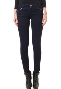 Jeans ajustados de denim oscuro con hardware en tono dorado, bolsillos frontales en ángulo y acentos de tachuelas. Terminan con una cintura alta y tela elástica.