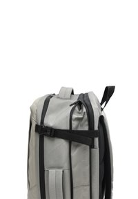 Vaaleanharmaa reppu, jossa on useita vetoketjullisia osastoja ja musta säädettävä sivuhihna valkoista taustaa vasten.