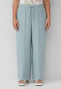 Pantalons bleu clair, amples, en tissu doux, avec une taille élastique et des détails de cordon de serrage. Silhouette évasée, longueur cheville.