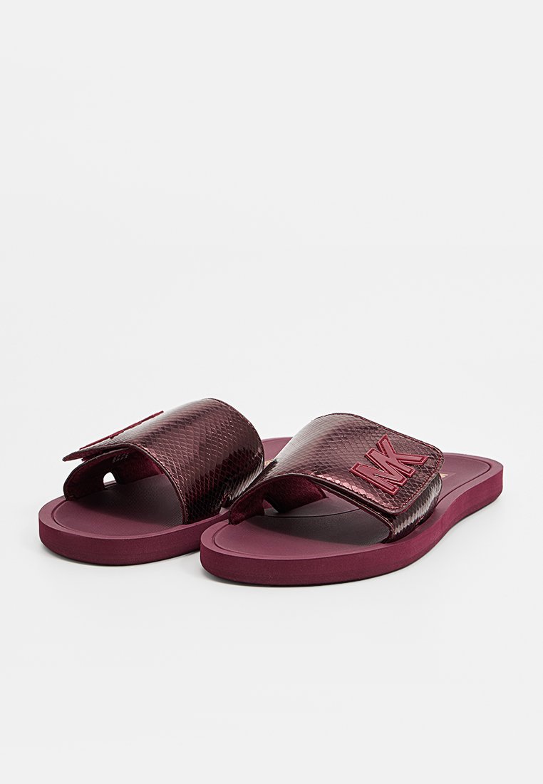 Bordowe klapki z teksturowanego materiału syntetycznego, charakteryzujące się wyraźnie wytłoczonym logo i gładką gumową podeszwą. Płaski, otwarty fason.