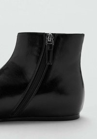 Cizme negre din piele ecologică până la glezne, cu fermoar pe lateral, vârf rotund și textură netedă. Designul este elegant, având un toc jos și plat.