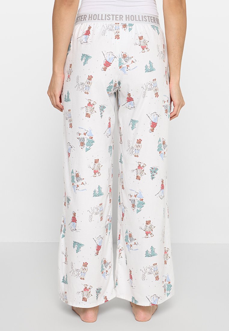Weiße Schlafanzughosen mit lockerer Passform, die farbenfrohe Cartoon-Muster von Bären in Winterlandschaften zeigen und einen elastischen Bund mit Logo haben.