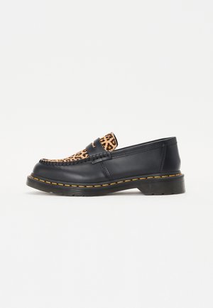 Mocasín negro de cuero con panel de estampado de leopardo en la parte superior, costuras amarillas alrededor de la suela y suela exterior gruesa de goma negra.