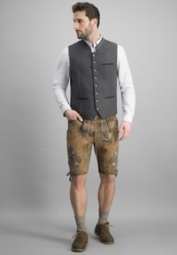 Grahamweste mit blauen Akzenten, weißes Hemd, braune Lederhosen mit floralen Stickereien, knielange Socken und braune Schuhe.