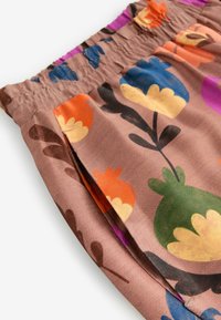 Färgglad blommönstrad tyg, med gröna, blå, orange och gula blommor på en brun bakgrund, med en rynkad elastisk midja.