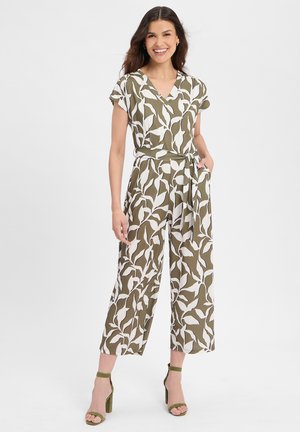 Olivgrüner Overall mit weißem Blattmuster, kurzen Ärmeln, V-Ausschnitt, Bindegürtel in der Taille, weitem Bein und Seitentaschen, kombiniert mit grünen High Heels.