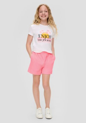 White t-shirt with printed "ENJOY THE JOURNEY" and palm trees, paired with pink textured shorts. White sneakers complete the outfit.