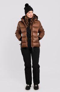 Veste en duvet marron avec capuche, dotée de poches latérales zippées et d'une texture matelassée, associée à un pantalon noir et à un bonnet en tricot noir.