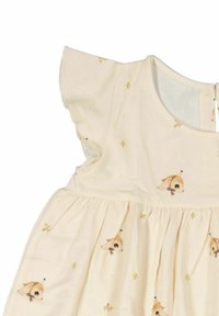 Krämliknande bomullsmodell med flygande ärmar, prydd med ett mönster av små djuransikten och guldiga stjärndetaljer, rynkad vid midjan.