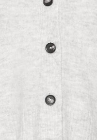 Helehall kardigan pehme tekstuuriga, ees kuus musta nööpi sulgemiseks.