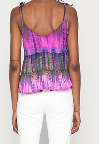 Top bez rękawów w intensywnym fioletowym, zielonym i różowym wzorze tie-dye. Posiada warstwowy fason oraz regulowane ramiączka.
