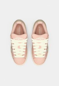 Ροζ σουέντ αθλητικά παπούτσια με μπεζ κορδόνια, στρογγυλή μύτη και λαστιχένια σόλα. Φέρουν την επωνυμία Adidas στη γλώσσα και στην πλευρά.