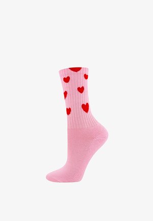 Chaussettes roses avec un design côtelé et des cœurs rouges éparpillés. Le tissu semble doux avec une texture lisse, et une longueur classique jouant sur le style crew.