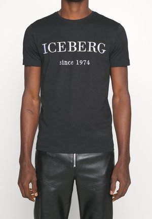 Camiseta de algodón negra con cuello redondo, con el texto blanco "ICEBERG desde 1974" centrado en el frente. Mangas cortas y corte regular.