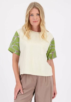 Korte mouw, crèmekleurig T-shirt met een groen patroon op de mouwen en een borstzak. Gemaakt van zachte katoen stof.