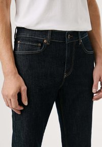 Tmavé denimové džínsy so rovnými nohavicami, s medenými doplnkami, kontrastným prešívaním a dizajnom s piatimi vreckami.