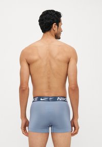 Svijetloplave bokserice s tamnoplavim Nike logom na pojasu, izrađene od glatkog materijala. Dizajnirane za blisko pristajanje uz tijelo, minimalna pokrivenost.