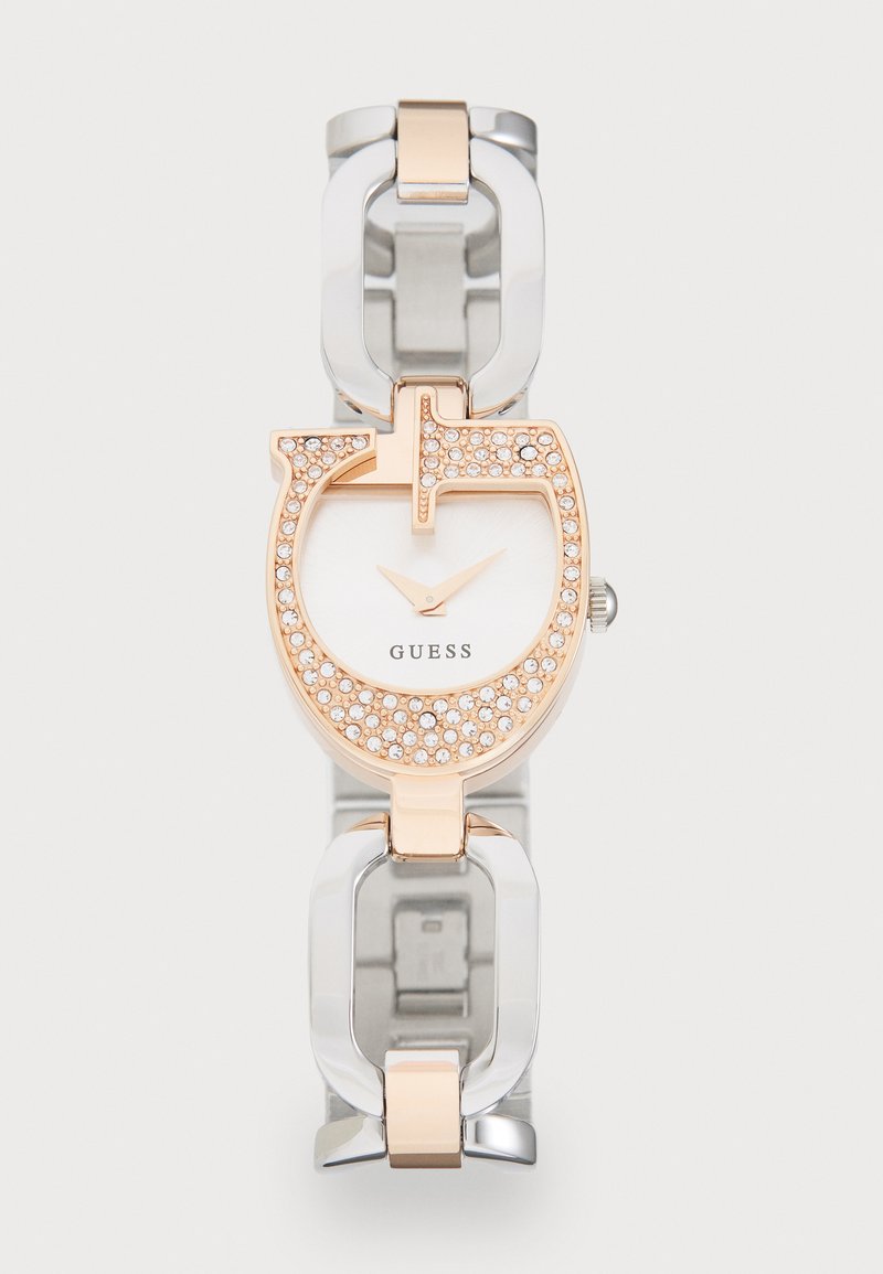 Rosa gull og sølv klokke med en sirkulær urskive, krystallaksenter og armbånd av metallkjede. Har en hvit skive og minimalistiske timemarkører.