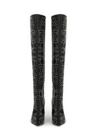 Botas negras hasta la rodilla con un acabado de cuero elegante, adornadas con patrones de tachuelas blancas y un diseño de punta afilada.