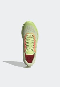 Chaussure de sport vert clair avec des accents orange, dessus en mesh, lacets attachés et semelle intérieure rouge avec texte circulaire, vue de dessus.