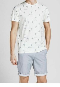 Bílá bavlněná tričko s potiskem světle modrých balónů a textem, v kombinaci s světle šedými šortkami se zabočenými manžetami a jemnou strukturou.